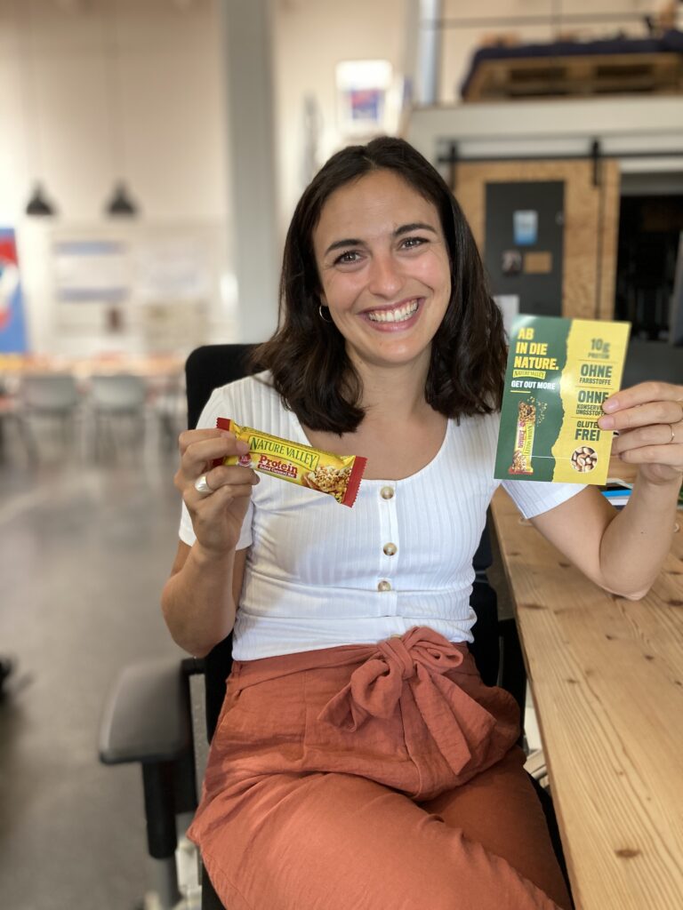 Nature Vally ambasador holding te bar with an advertisement leaflet. 