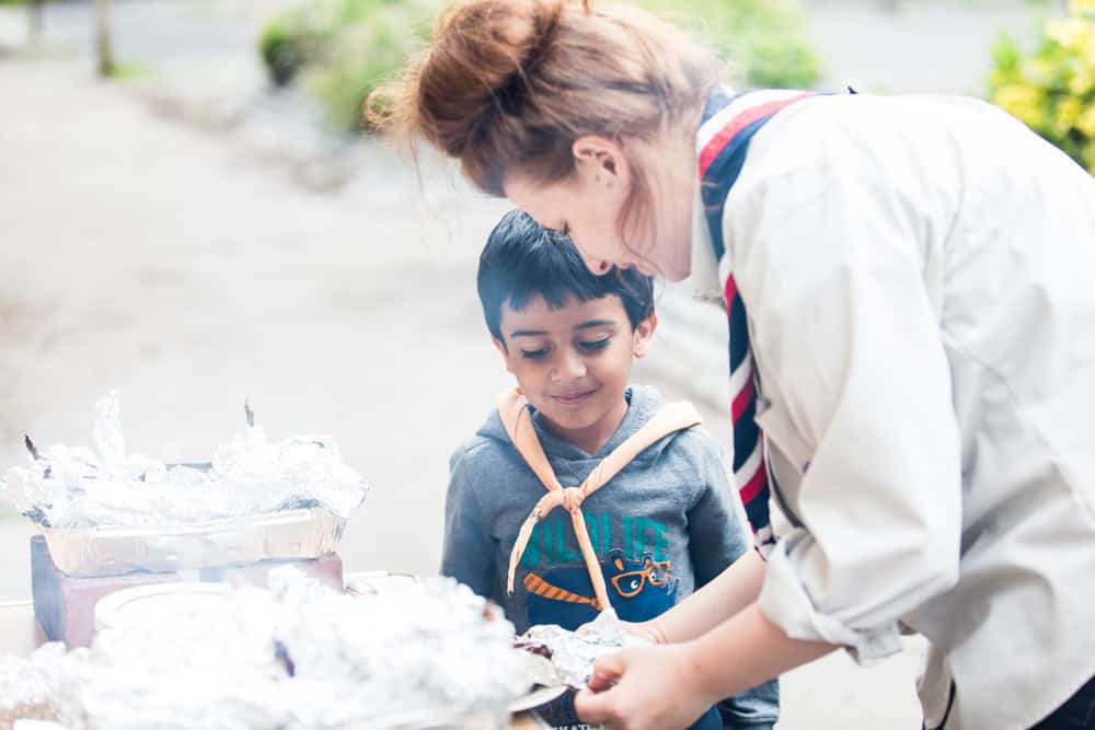 Child and woman sharing a cake outdoors.